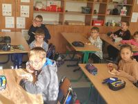 Uczniowie klasy II jedzą w ławkach jesienny posiłek