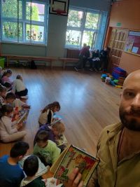 Nauczyciel i dzieci czytają książki.