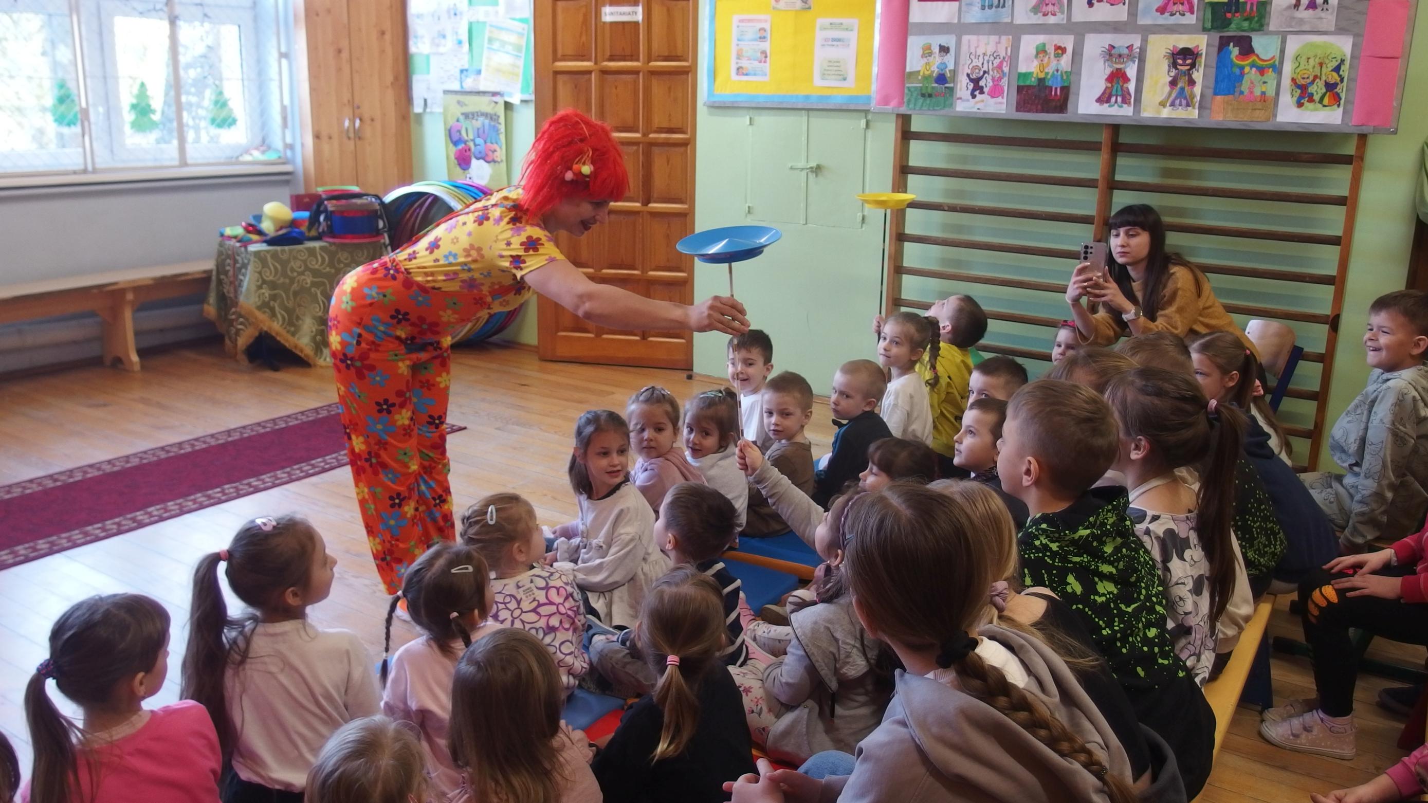 Klaun daje dzieciom kręcące się talerze do potrzymania